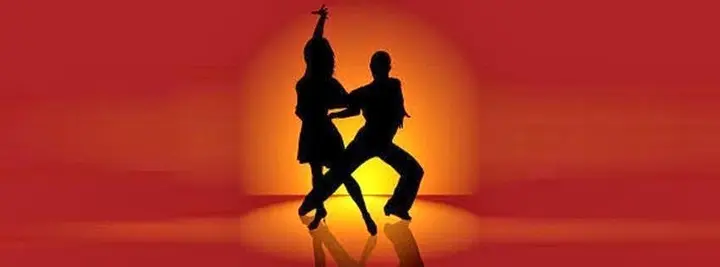 Bannière orange où deux danseurs latino en silhouette posent devant un soleil couchant.